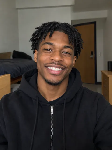 Selfie of a smiling young Black man with short twists in a black hoodie